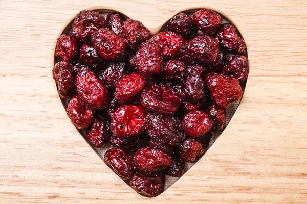 Dried cranberry fruit heart shaped on wood board