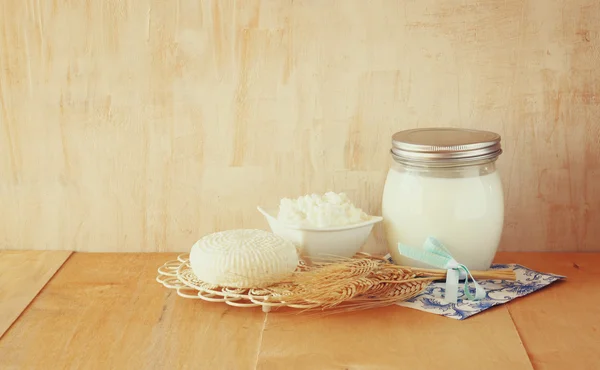 Greek cheese , cottage and milk on wooden table over wooden textured background. Symbols of jewish holiday - Shavuot