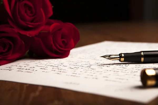 Still life of a fountain pen, paper and flowers roses