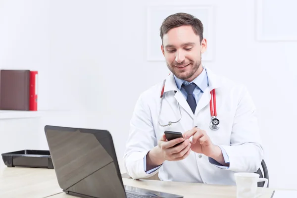 Smiling cardiologist holding the mobile phone