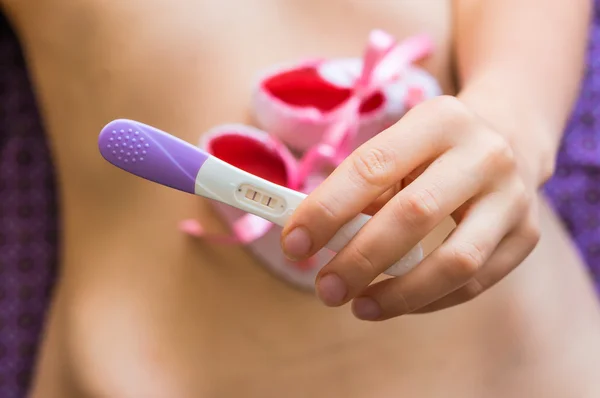 Pregnant woman holding a pregnancy test