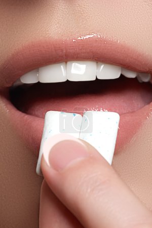 Closeup detail of woman putting pink chewing gum into her mouth. Chewing Gum, Eating, Women. Close up on a beautiful girl while enjoying a candy._高清图片_邑石网